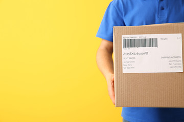 Delivery man with box on color background, closeup