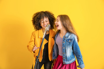 Wall Mural - Teenage girls with microphone singing against color background