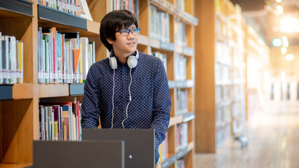 Wall Mural - Young Asian man university student pushing book cart in college library finding textbook for education research. Bestseller collection in bookstore. Scholarship or educational opportunity concepts