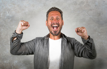 Wall Mural - portrait of young happy and attractive Caucasian man gesturing with fist raising arms in victory and success sign smiling cheerful excited feeling strong emotion