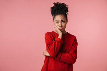 Amazing sad confused young african woman posing isolated over pink wall background.