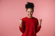 Beautiful young excited african woman posing isolated over pink wall background make winner gesture.