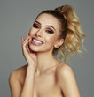 Beautiful smile of blond woman with white teeth touching her cheeks