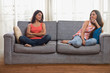 © IndiaPix - Two teenage girls sitting on two ends of a sofa looking at each other