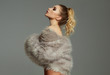 © kiuikson - Photo of blond female model with faux fur and tied hair isolated on gray background
