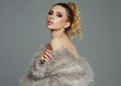 © kiuikson - Photo of blond female model with fur and tied hair looking at camera isolated on gray background