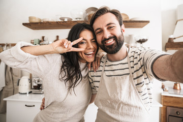 Sticker - Portrait of positive couple taking selfie photo while cooking in kitchen at home