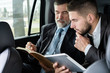 © opolja - business colleagues discussing business ideas while sitting in backseat of the car or taxi.