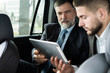 © opolja - business colleagues discussing business ideas while sitting in backseat of the car or taxi.