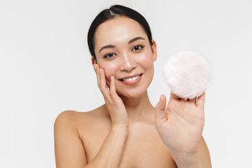 Poster - Beautiful young pretty asian woman with healthy skin posing naked isolated over white wall background holding powder puff.