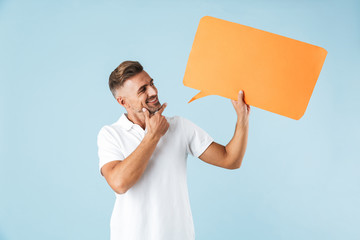 Sticker - Excited emotional adult man posing isolated over blue wall background holding speech bubble.