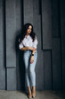 © dimadasha - Photo session of a young brunette in jeans and a white shirt.