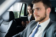 © opolja - Success in motion. Handsome young man in full suit smiling while driving a car.