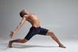 © nazarovsergey - Photo of a handsome man ballet dancer, dressed in a black shorts, making a dance element against a gray background in studio.