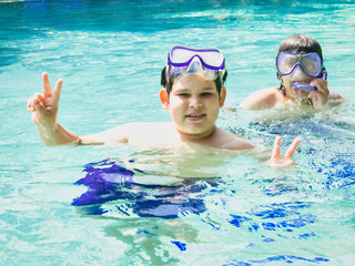 summer holidays and teenage concept - close up of brothers hands showing v-sign with fingers in the ocean transparent water.