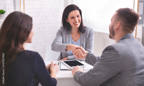 Cuadros en Lienzo Smiling female insurance broker and young family shaking hands