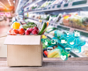Online grocery concept. Shopping order online ingredients food for cooking and packages box with icon media on wood table on supermarket background and food delivery service for lifestyle in city.