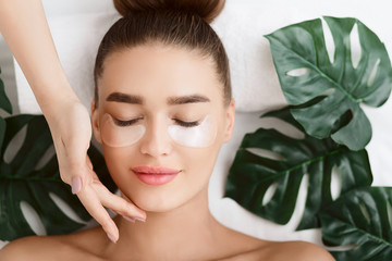 woman with eye patches, relaxing in spa center