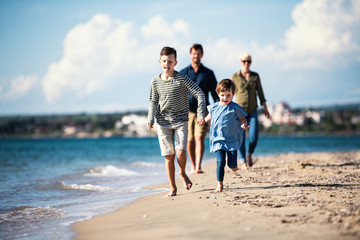 Young family with two small children walking outdoors on beach.