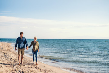 Wall Mural - Young couple walking outdoors on beach, holding hands. Copy space.