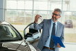 © cherryandbees - car dealer agent holding car keys in car showroom
