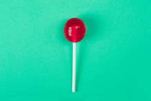 A Red Lollipop On A Stick At The Green Background, A View From Above, Sweets And Caramel.