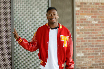 Wall Mural - Male High School Senior in Red Letterman Jacket for Sports standing in an Urban Area