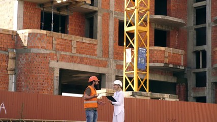 Relationships between construction clients and participants building industry. Woman engineer and builder communicate at construction site. Discussing plan. Construction team communication concept.