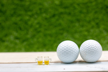 Two glasses of beer with golf ball on green grass