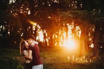 Amazing couple embracing and hugging against sunset light in the park while walking after work.