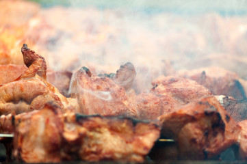 Roasted meat on skewers in smoke close up