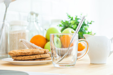 Empty сup, milk jug, cookies and fruit on the kitchen table. Making breakfast, good or healthy morning.