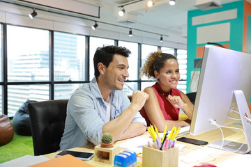 caucasian businessman and businesswoman in smart casual wear working on computer on wood desk in creative office with happy face