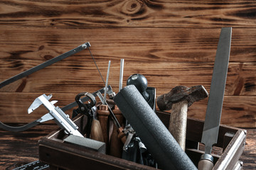 Box with set of carpenter's tools on wooden background