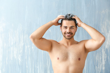 Handsome man washing hair on grey background