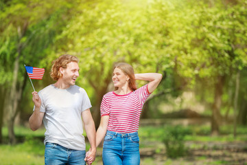 Wall Mural - Happy young couple with USA flag outdoors. Independence Day celebration