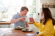 Young Downs Syndrome Couple Enjoying Tea And Cake In Kitchen At Home