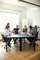 Wall Mural - Group of diverse designers talking together around an office tab