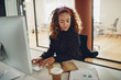 © Flamingo Images - Businesswoman reading notes and working on her office computer