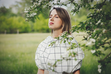 Poster - young woman in a checkered dressstay near a flowering tree