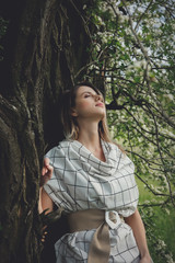 Poster - young woman in a checkered dressstay near a flowering tree