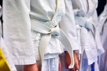 Concept karate, martial arts. Construction of students in the hall before training. Kimono, different belts, different levels of training. Close up,