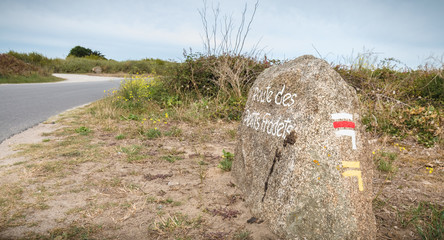 Petit Fradets road painted on a large stone indicating a hiking path by the sea