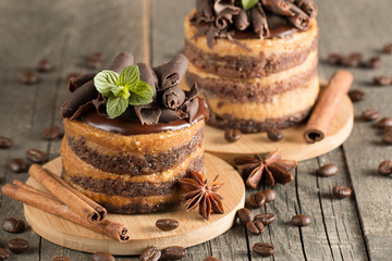 Wall Mural - Dark chocolate cakes on black slattern board with mint, cinnamon, coffee beans on a wooden  background. Tasty dessert food concept.