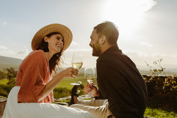 Poster - Couple sitting near a vineyard on a date drinking wine