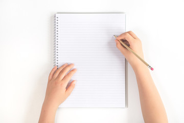 Hands on a desk with a pencil writing on a blank notebook isolated on white background. Flat lay with copy space for bloggers or education advert top view