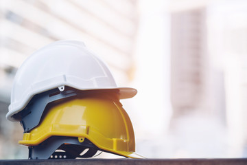 Wall Mural - yellow and white hard safety wear helmet hat in the project at construction site building on concrete floor on city with sunlight. helmet for workman as engineer or worker. concept safety first. 