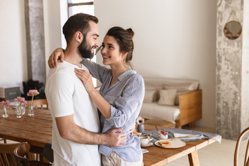 Poster - Photo of excited brunette couple in love smiling while hugging together in apartment