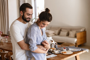 Wall Mural - photo of joyful brunette couple in love smiling while hugging together in apartment