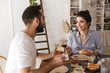 © Drobot Dean - Image of lovely brunette couple eating together at table while having breakfast in apartment